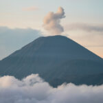 Mount Bromo emitting smoke, surrounded by clouds