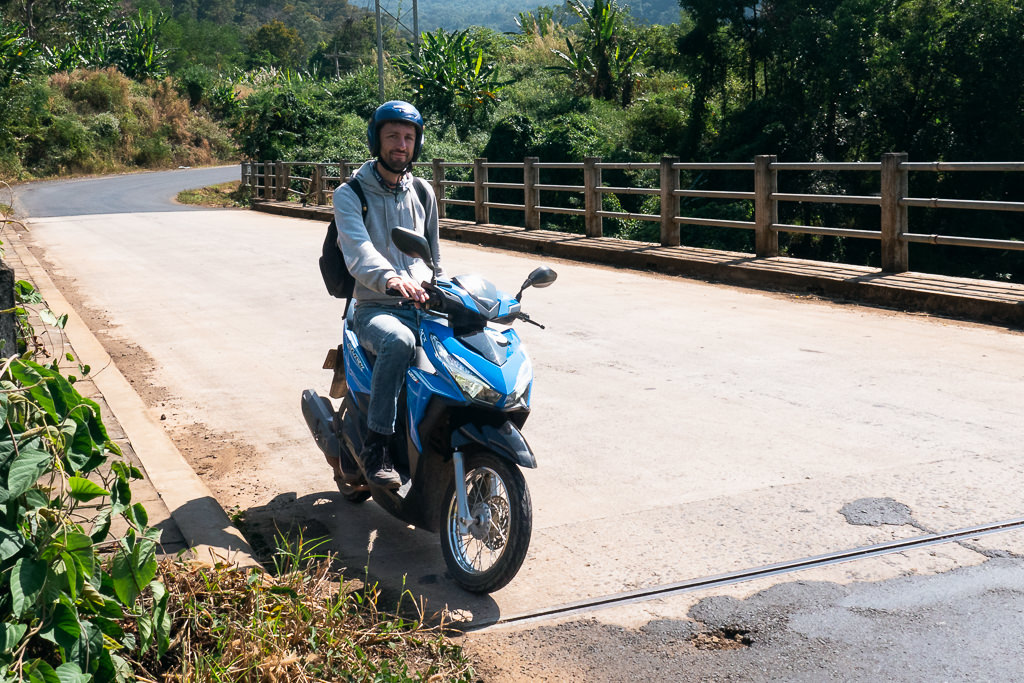 A man riding a blue motorcycle in Laos.