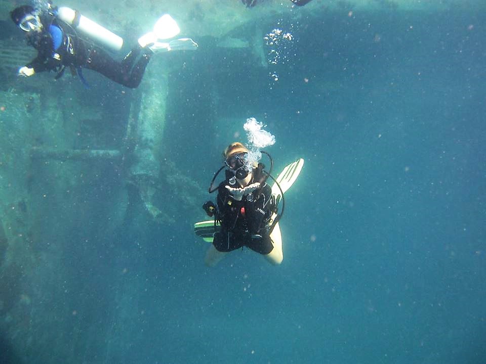 Two scuba divers swim near wrecks